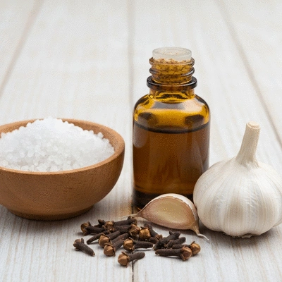 Assortment of natural home remedies for toothache including salt, clove oil, and garlic
